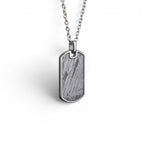 The Field Tag — angled view showing the titanium-grade steel frame and polished edges.