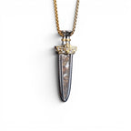The Pallas Blade — detail of the hand-engraved gold-tone hilt set against a polished steel body.