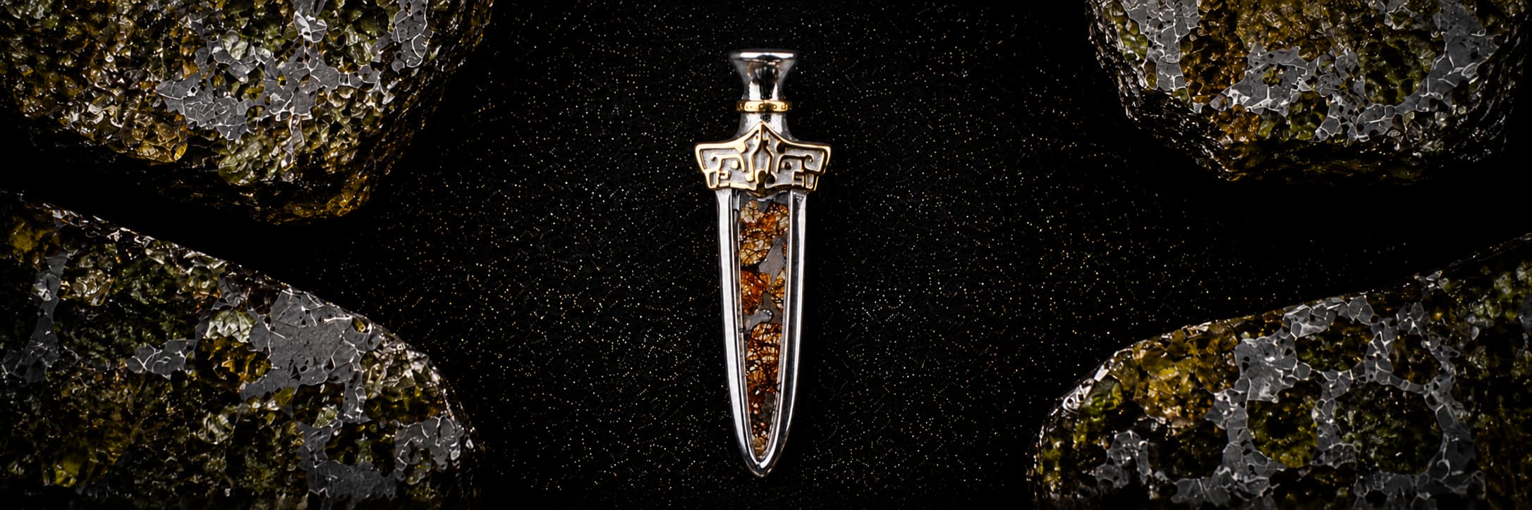 The Pallas Blade — Sericho pallasite pendant with hand-engraved gold-tone hilt and amber-gold olivine crystals, photographed against a dark backdrop